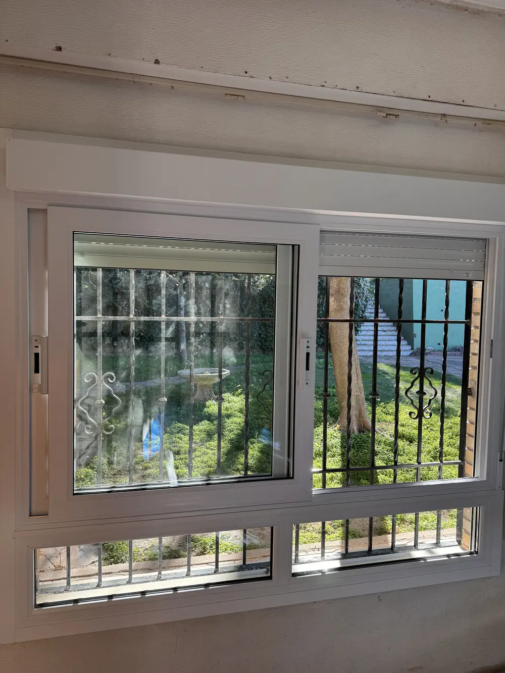 Ventana de PVC nueva instalada, con persiana y reja