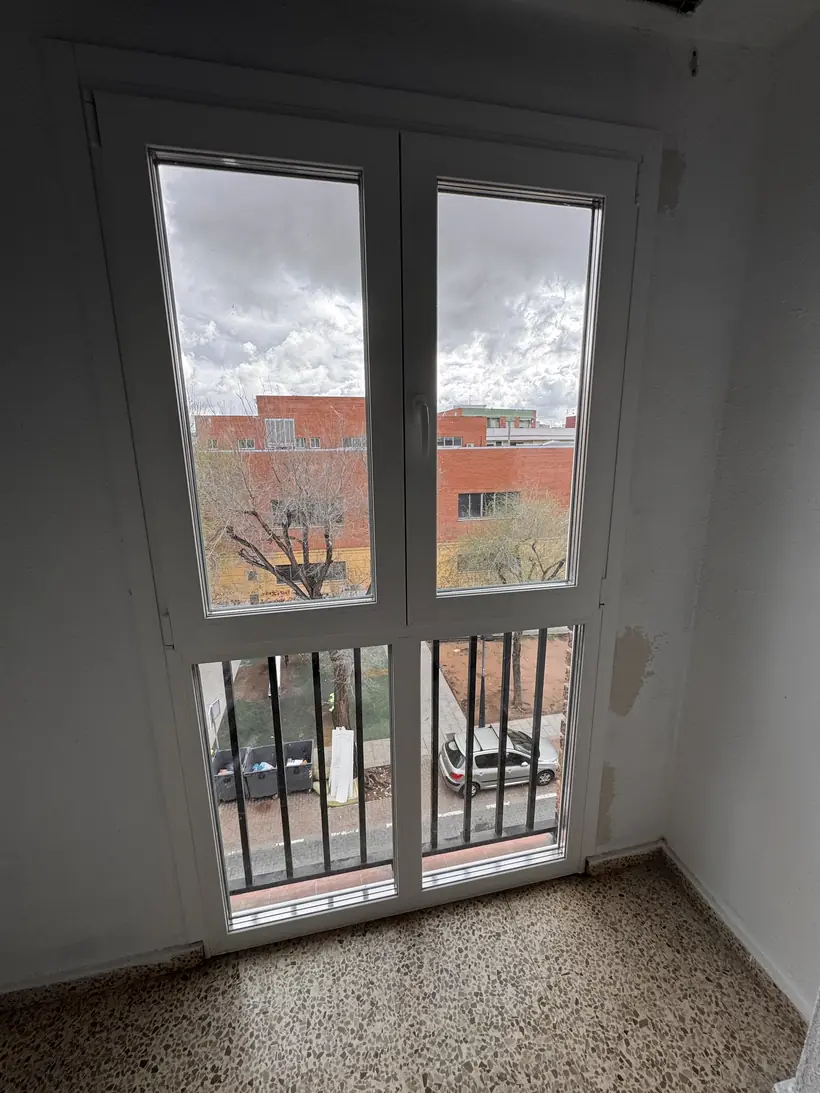 Puerta balconera blanca con reja, ya instalada
